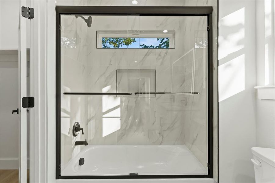 Full bath featuring enclosed tub / shower combo and toilet