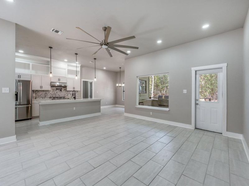 Unfurnished living room featuring ceiling fan and a chandelier