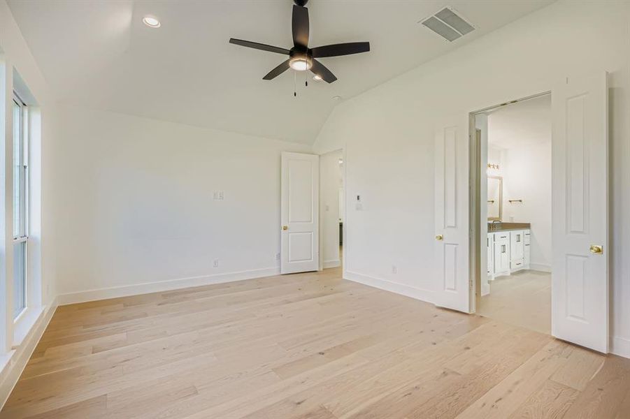Unfurnished bedroom featuring light wood-type flooring, vaulted ceiling, ceiling fan, ensuite bathroom, and recessed lighting Unfurnished bedroom featuring light wood-type flooring, vaulted ceiling, ceiling fan, ensuite bathroom, and recessed lighting