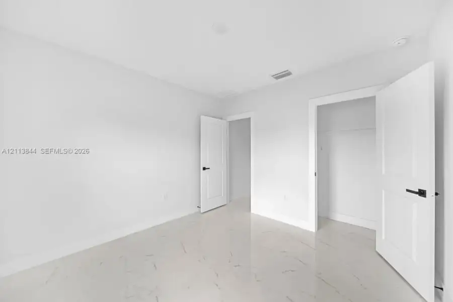 Polished stone-finish tile flooring, white shaker-style interior doors, and matte black lever handles Polished stone-finish tile flooring, white shaker-style interior doors, and matte black lever handles