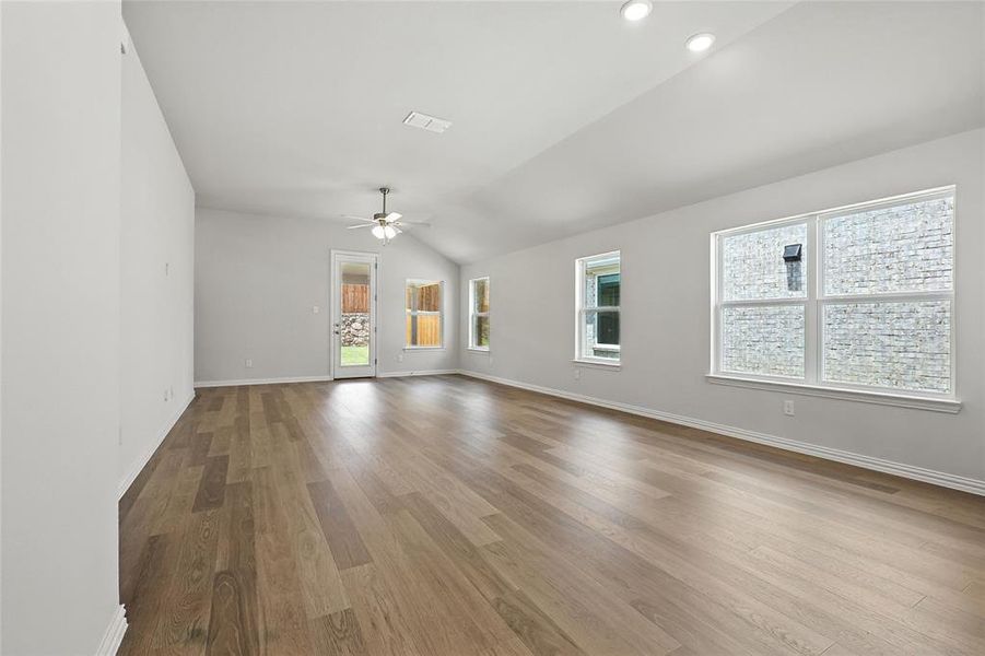Unfurnished living room with ceiling fan, vaulted ceiling, wood finished floors, and recessed lighting Unfurnished living room with ceiling fan, vaulted ceiling, wood finished floors, and recessed lighting