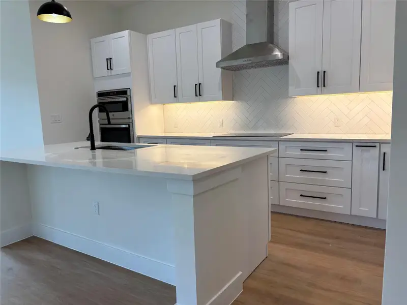 A well-appointed kitchen features a waterfall island, built-in ovens, and sleek cabinetry. A well-appointed kitchen features a waterfall island, built-in ovens, and sleek cabinetry.