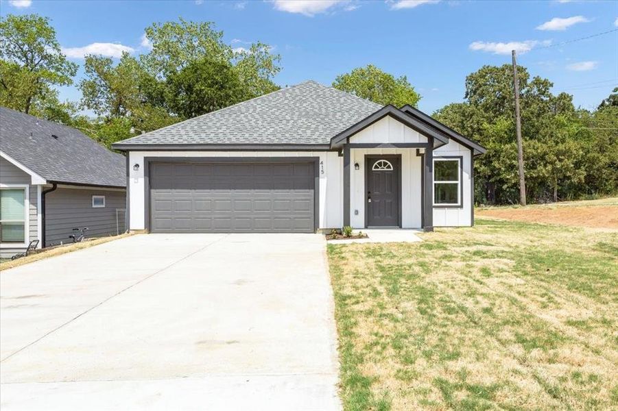 View of front of home with a garage and a front lawn