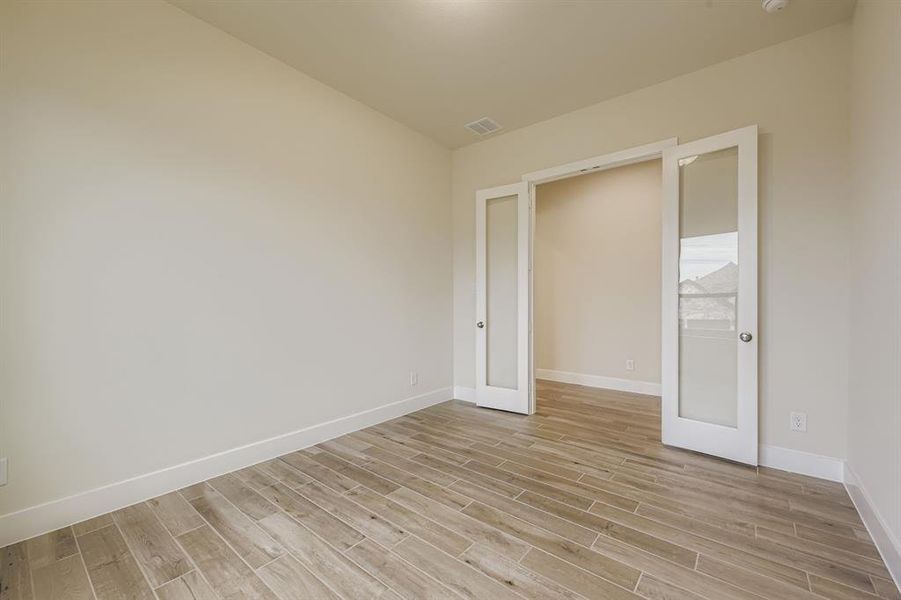 Empty room featuring french doors and light wood-style flooring