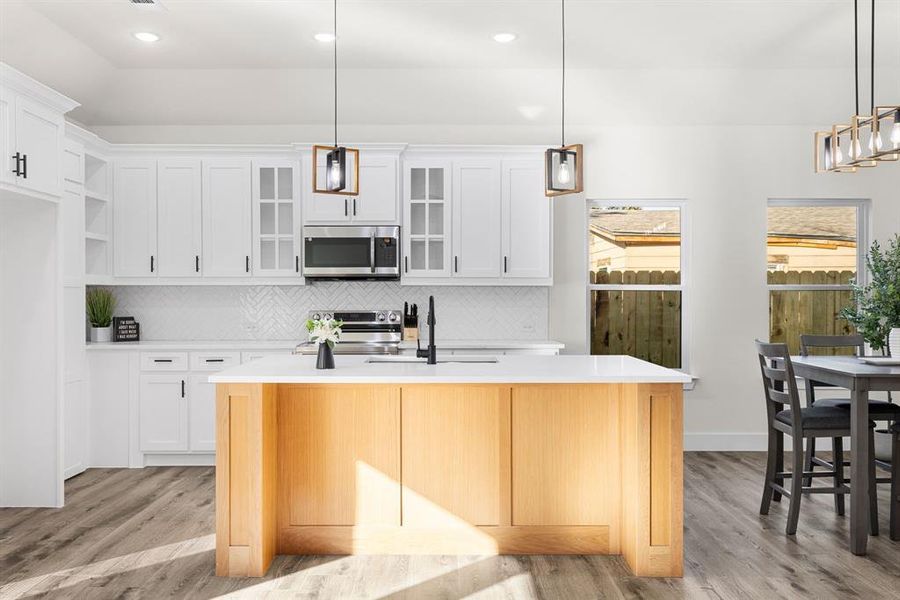 Kitchen with pendant lighting, sink, stainless steel appliances, and an island with sink