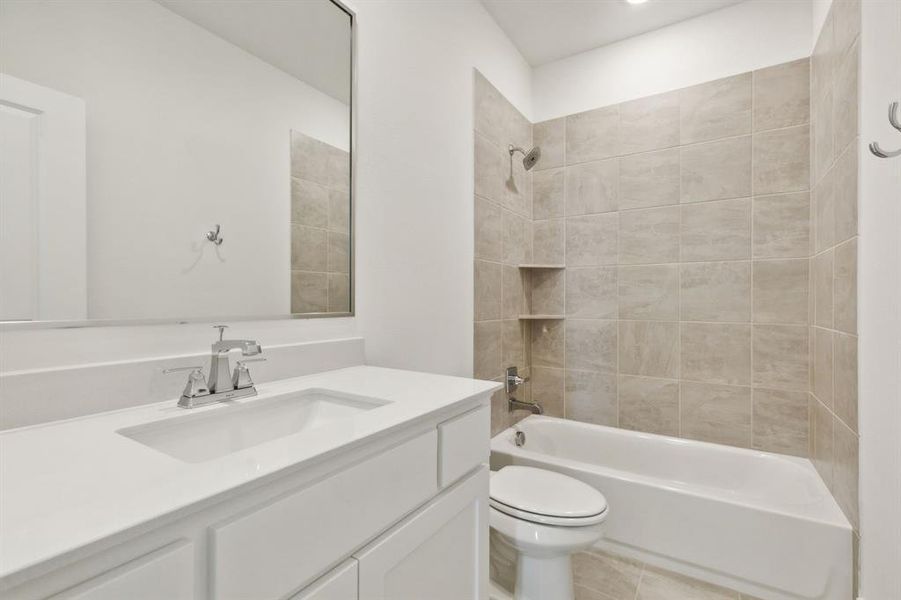 Bathroom featuring a white vanity with an integrated sink, polished chrome faucet, a rectangular mirror, a bathtub with a tiled surround, and integrated shelving Bathroom featuring a white vanity with an integrated sink, polished chrome faucet, a rectangular mirror, a bathtub with a tiled surround, and integrated shelving
