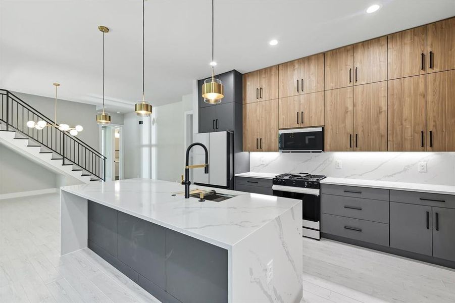 Kitchen with gray cabinetry, pendant lighting, range with gas stovetop, light stone counters, and recessed lighting