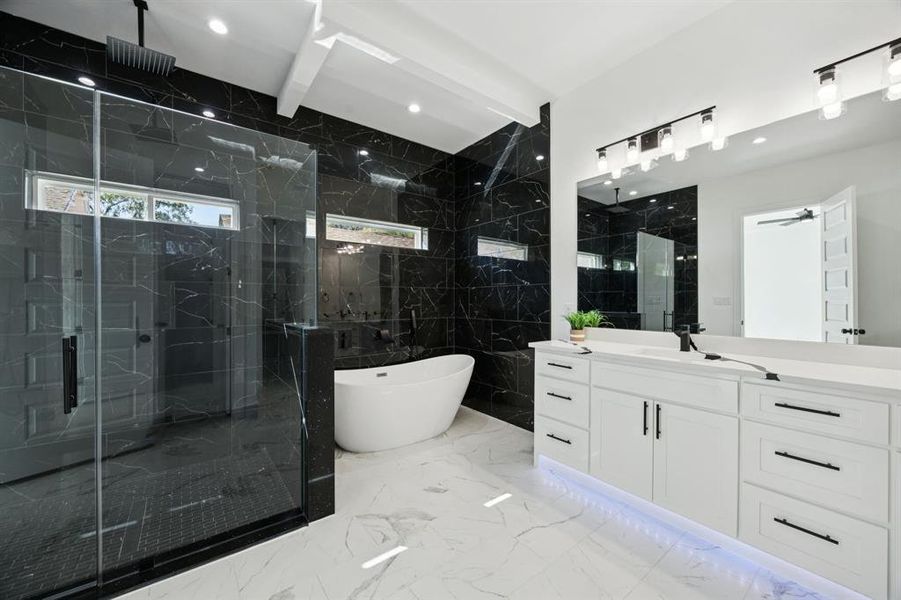 Bathroom with a soaking tub, light marble finish floors, tile walls, vanity, and a marble finish shower