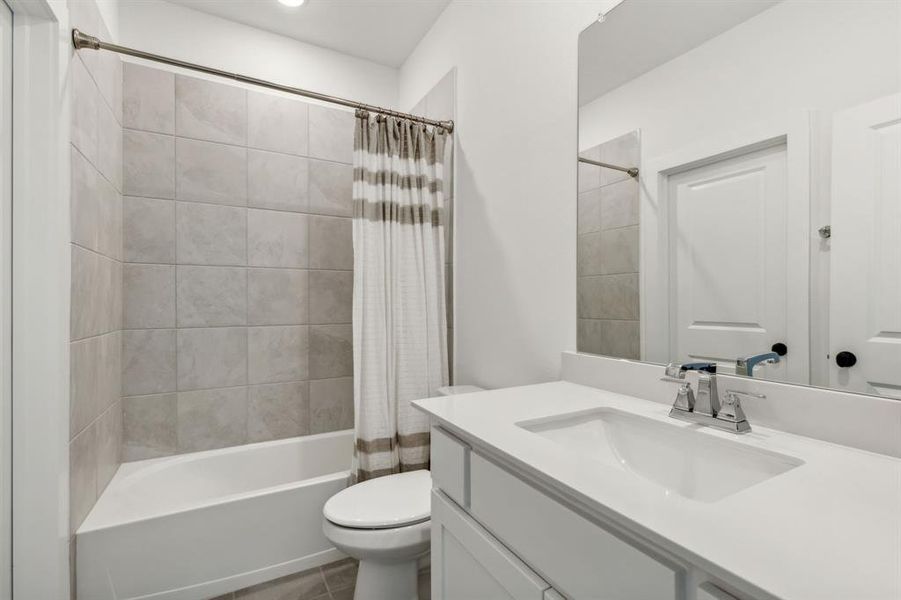 Guest Bathroom featuring vanity, toilet, tile patterned floors, and shower / bath combo with shower curtain