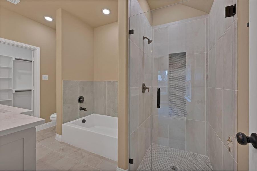 Full bath featuring toilet, a garden tub, vanity, and a stall shower Full bath featuring toilet, a garden tub, vanity, and a stall shower
