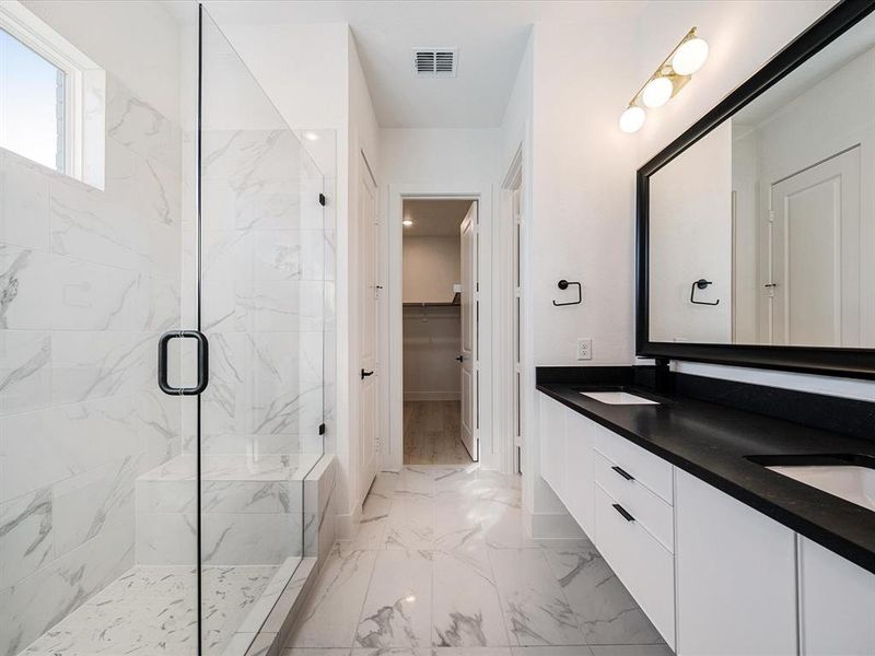 Full bathroom featuring a walk in closet, a marble finish shower, double vanity, and light marble finish floors