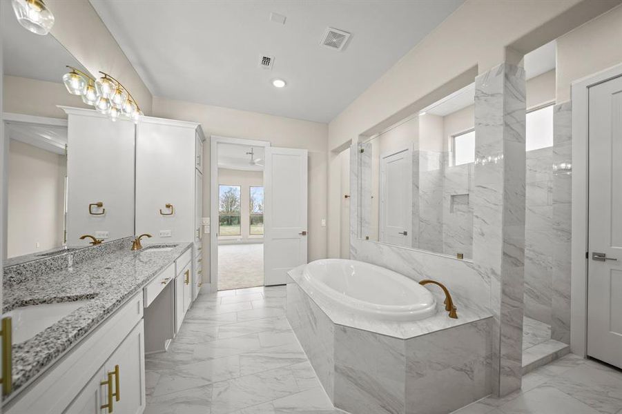 This bathroom boasts tile floors, a vanity area, recessed lighting, a large mirror, granite countertops, double sinks, and plenty of wooden cabinetry.