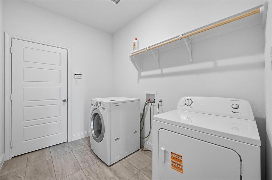 Laundry area featuring washing machine and dryer and light tile patterned floors