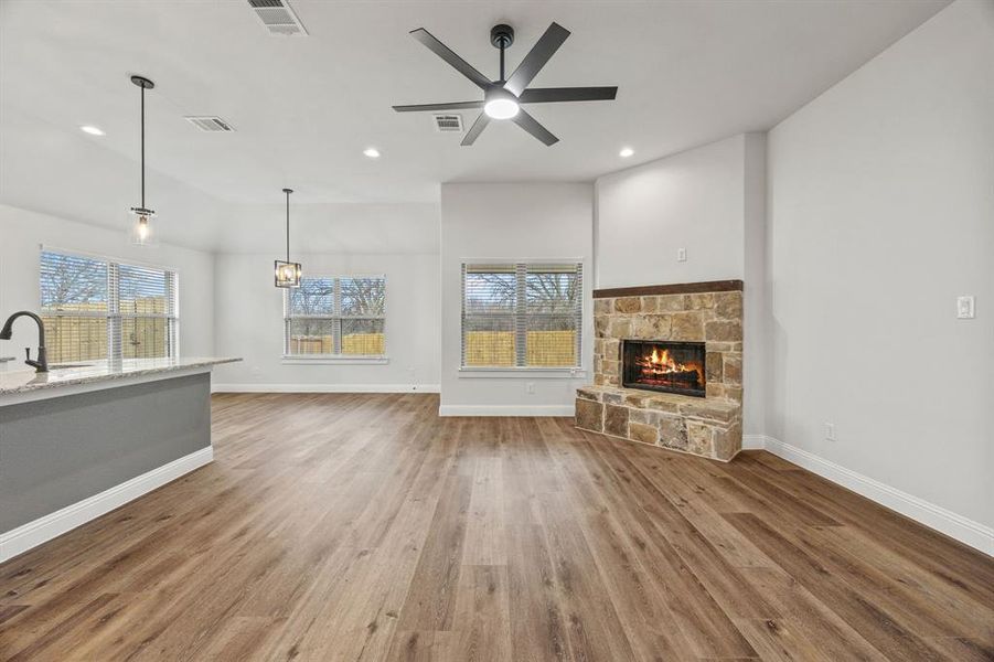 Unfurnished living room with light wood-style flooring, a fireplace, a ceiling fan, recessed lighting, and lofted ceiling
