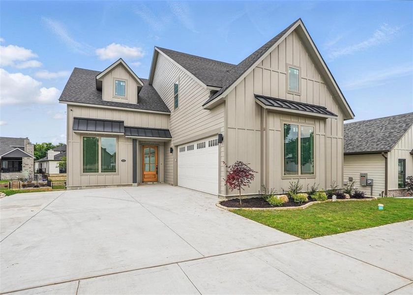 Modern farmhouse with board and batten siding, roof with shingles, a standing seam roof, and driveway Modern farmhouse with board and batten siding, roof with shingles, a standing seam roof, and driveway