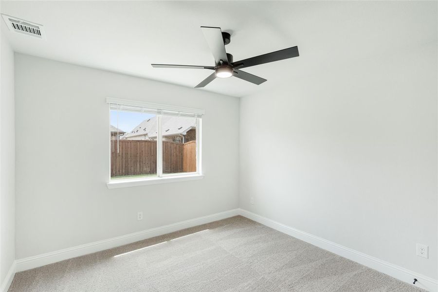Empty bedroom with vaulted ceiling, black ceiling fan, carpet flooring, and single window