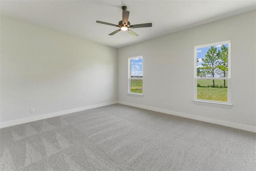 Spacious room featuring light gray carpeting, two large windows with white trim, and a contemporary ceiling fan with integrated lighting Spacious room featuring light gray carpeting, two large windows with white trim, and a contemporary ceiling fan with integrated lighting