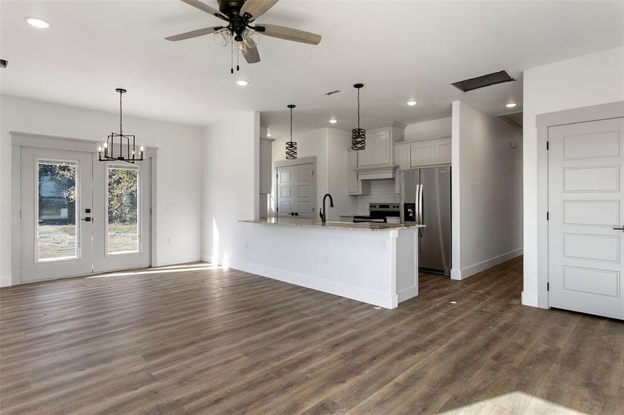 Kitchen with pendant lighting, light stone countertops, kitchen peninsula, and stainless steel appliances