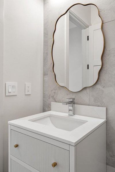 Bathroom vanity featuring a polished chrome faucet, integrated rectangular sink, and a white countertop with a matching backsplash