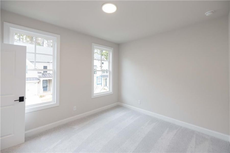 Empty room featuring light colored carpet and baseboards