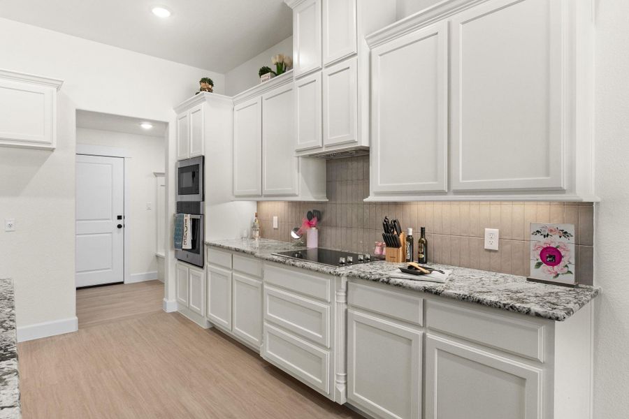 Kitchen featuring white cabinetry, light stone counters, light wood finished floors, and recessed lighting