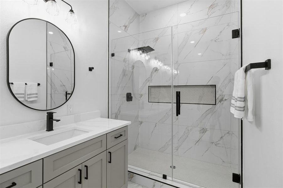 Contemporary bathroom featuring a spacious glass-enclosed shower with large format tile, a built-in shower niche, and matte black fixtures
