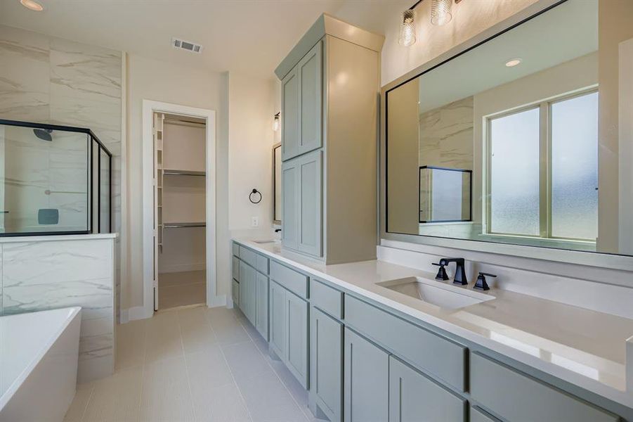 Full bathroom featuring double vanity, a freestanding tub, a walk in closet, a marble finish shower, and recessed lighting Full bathroom featuring double vanity, a freestanding tub, a walk in closet, a marble finish shower, and recessed lighting
