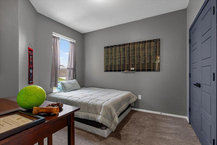 A comfortable bedroom with carpeted flooring and ample natural light from a well-sized window.