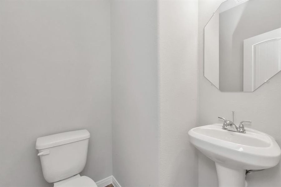 Simplicity meets function in this well-appointed powder room, perfect for guests and daily convenience. The clean lines, neutral tones, and modern fixtures create a space that is both practical and stylish. It's a small but significant feature that adds to the overall appeal of this thoughtfully designed home, offering both comfort and utility in a compact setting. **This image is from another Saratoga Home with similar floor plan and finishes, not the June floorplan.**