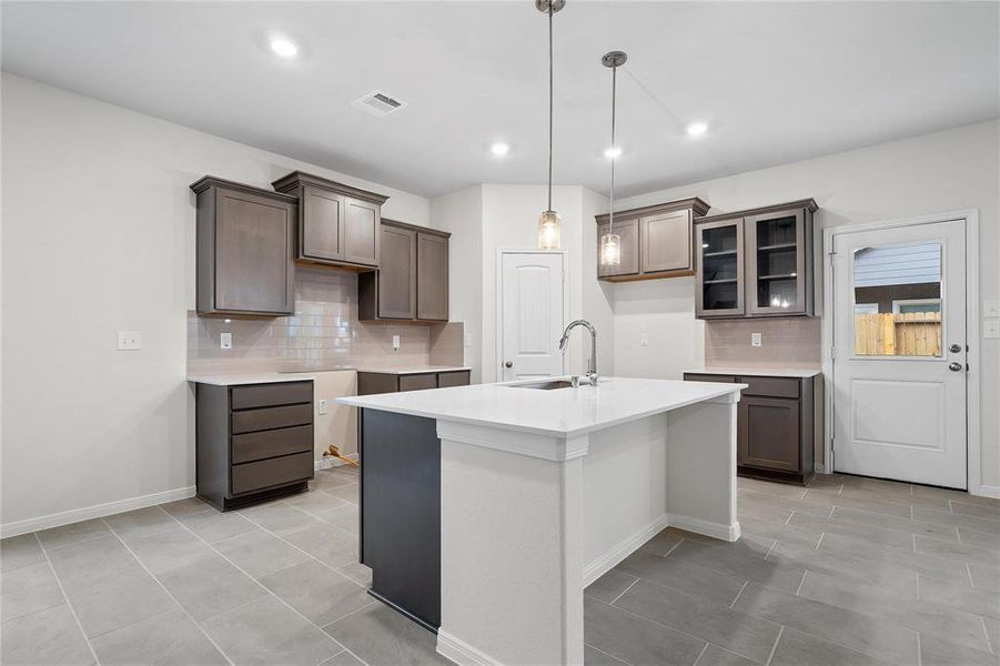 Discover a culinary haven in this sleek kitchen, featuring modern cabinetry, expansive countertops, and a large island perfect for meal prep and casual dining. The contemporary design is complemented by elegant pendant lighting and ample storage, making this kitchen as functional as it is beautiful—a true centerpiece for the home. **This image is from another Saratoga Home with similar floor plan and finishes, not the Brayden floorplan.**