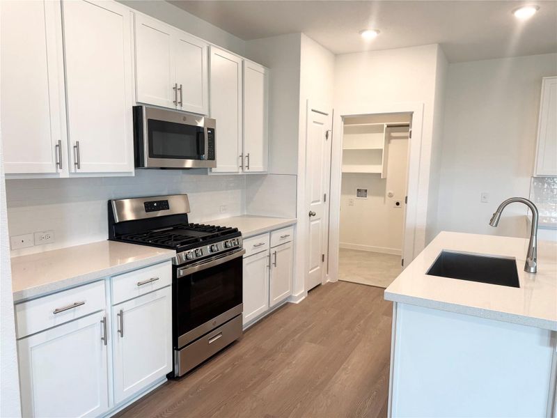 Kitchen with decorative backsplash, appliances with stainless steel finishes, white cabinetry, light stone countertops, and dark wood-type flooring Kitchen with decorative backsplash, appliances with stainless steel finishes, white cabinetry, light stone countertops, and dark wood-type flooring