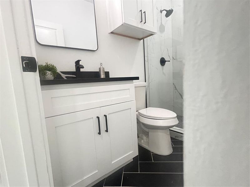 Bathroom with vanity, walk in shower, tile patterned flooring, and toilet