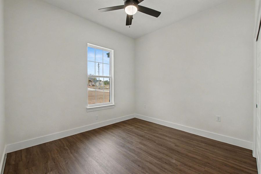 Spare room featuring dark wood-style flooring and ceiling fan