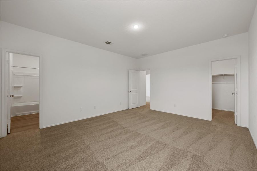 Unfurnished bedroom with a spacious closet, carpet flooring, and connected bathroom Unfurnished bedroom with a spacious closet, carpet flooring, and connected bathroom