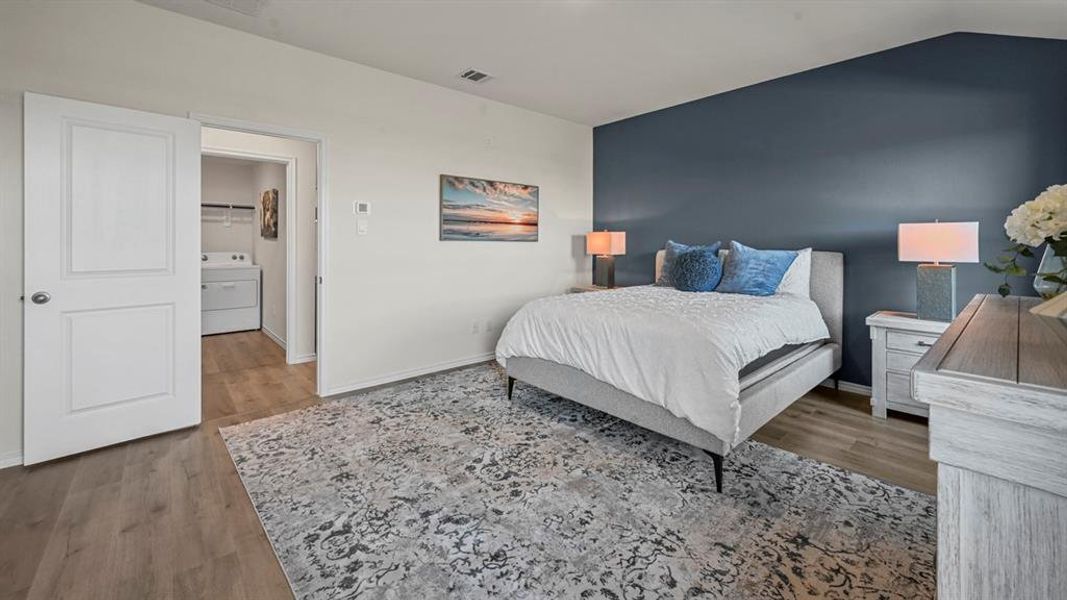 Bedroom with wood finished floors, washer / clothes dryer, and vaulted ceiling