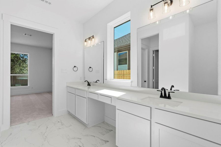 A dual vanity with ample counter space and elegant cabinetry provides plenty of room for two, with large mirrors and modern lighting that make the space feel bright and open.