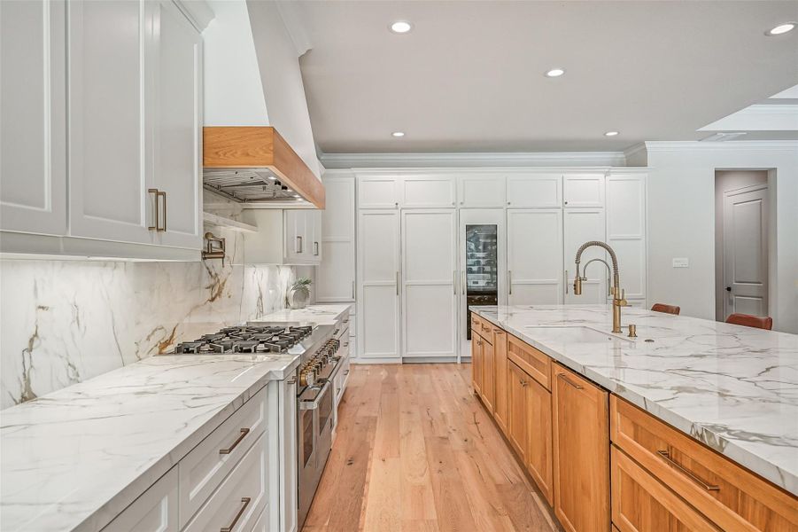 Designed for serious cooks, the kitchen pairs an expansive prep island with a professional-style gas range, pot filler and custom vent hood, while floor-to-ceiling cabinetry conceals the paneled refrigerator & freezer for a beautifully streamlined look.