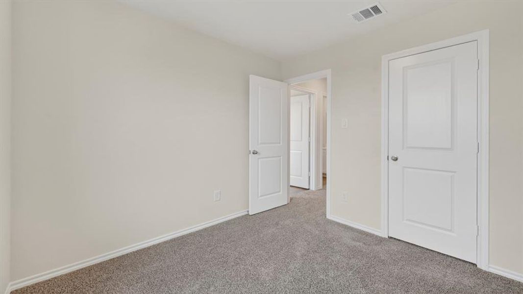 Neutral tone wall finish with white trim, gray textured carpeting, and white paneled doors with brushed nickel hardware