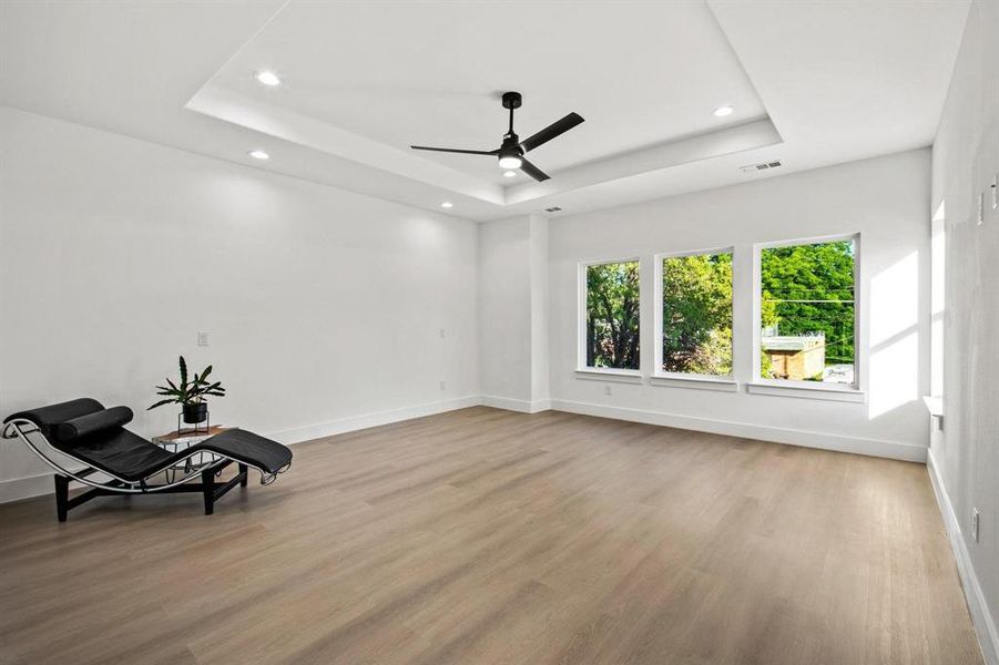 Sitting room with a raised ceiling, light wood finished floors, recessed lighting, and ceiling fan