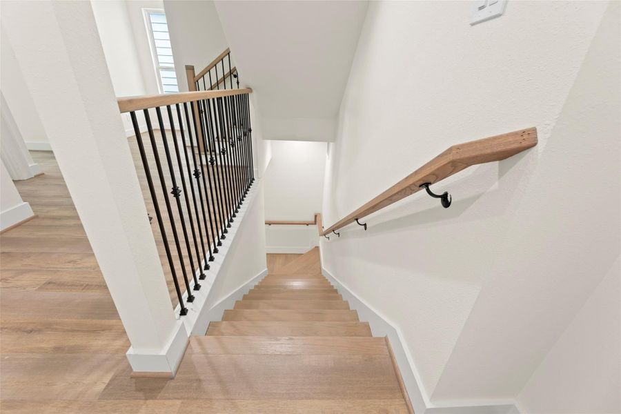 This photo features a modern staircase and a sleek black metal railing. The space is bright, with light walls and natural light filtering in, creating an inviting atmosphere.