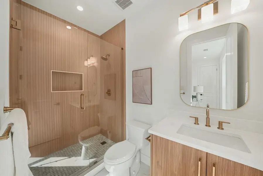 Bathroom featuring a glass-enclosed shower with fluted wood-finish wall panels and a built-in niche Bathroom featuring a glass-enclosed shower with fluted wood-finish wall panels and a built-in niche