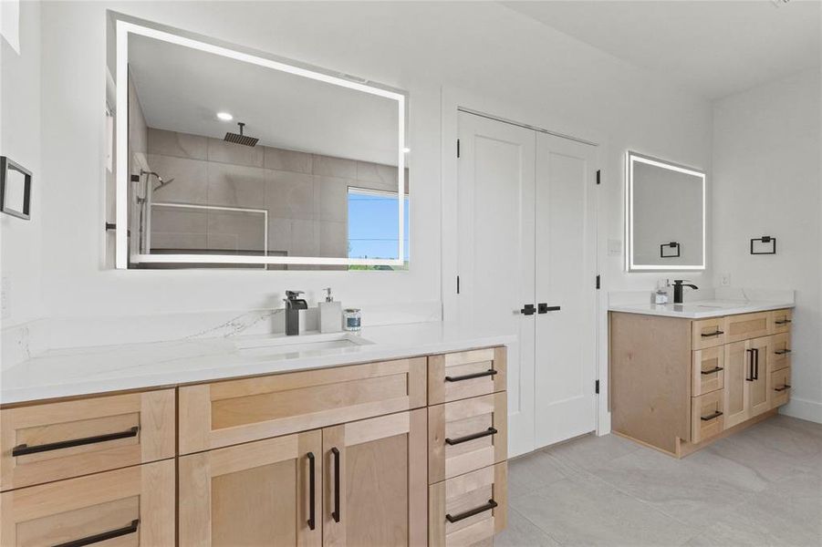 Bathroom with two vanities, a shower stall, and light tile patterned floors Bathroom with two vanities, a shower stall, and light tile patterned floors