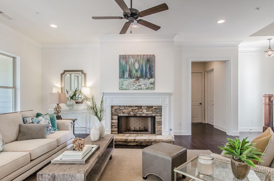 Living room with a stone fireplace, ornamental molding, wood finished floors, recessed lighting, and a ceiling fan Living room with a stone fireplace, ornamental molding, wood finished floors, recessed lighting, and a ceiling fan