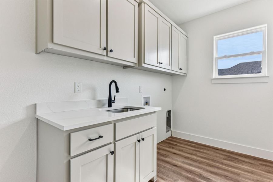 Laundry area featuring cabinet space, light wood-type flooring, hookup for a washing machine, and electric dryer hookup