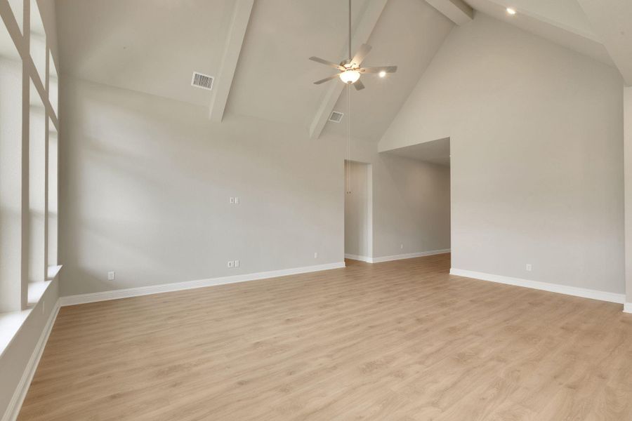 Unfurnished room with ceiling fan, light wood-style flooring, visible vents, baseboards, and beam ceiling Unfurnished room with ceiling fan, light wood-style flooring, visible vents, baseboards, and beam ceiling