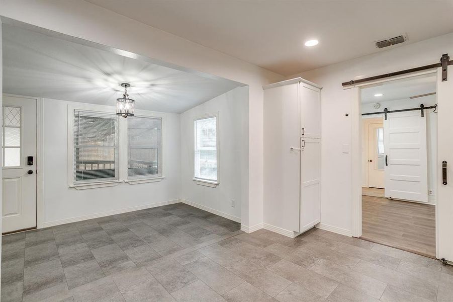 Unfurnished dining area featuring a barn door, recessed lighting, and decorative lighting