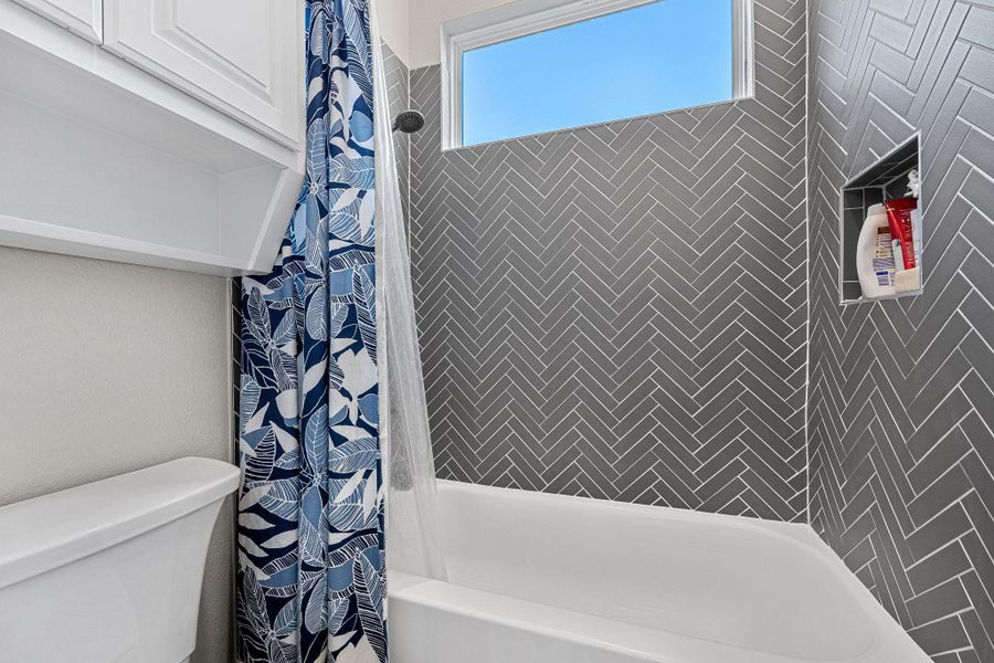 Herringbone tile and a transom window elevate this bright, functional bathroom. Herringbone tile and a transom window elevate this bright, functional bathroom.