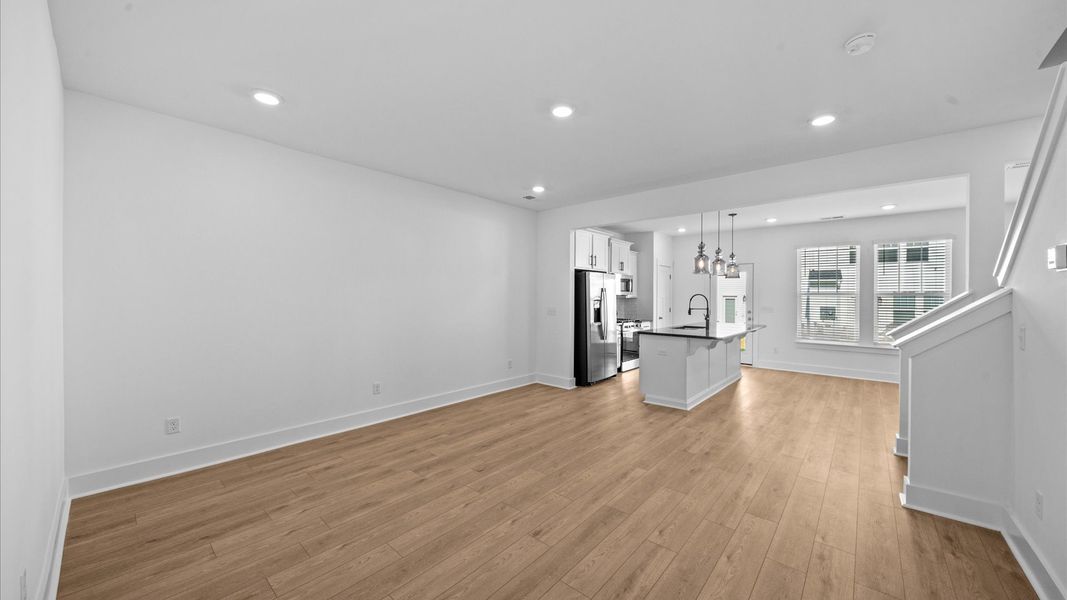 Elegant family room featuring hardwood flooring, large windows, and thoughtful architectural detail Elegant family room featuring hardwood flooring, large windows, and thoughtful architectural detail