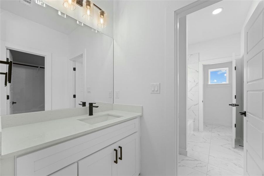 Full bathroom with marble look tile flooring, vanity, and tub / shower combination Full bathroom with marble look tile flooring, vanity, and tub / shower combination