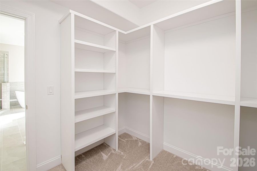 The spacious primary closet is outfitted with custom solid wood shelving for organized and stylish storage.